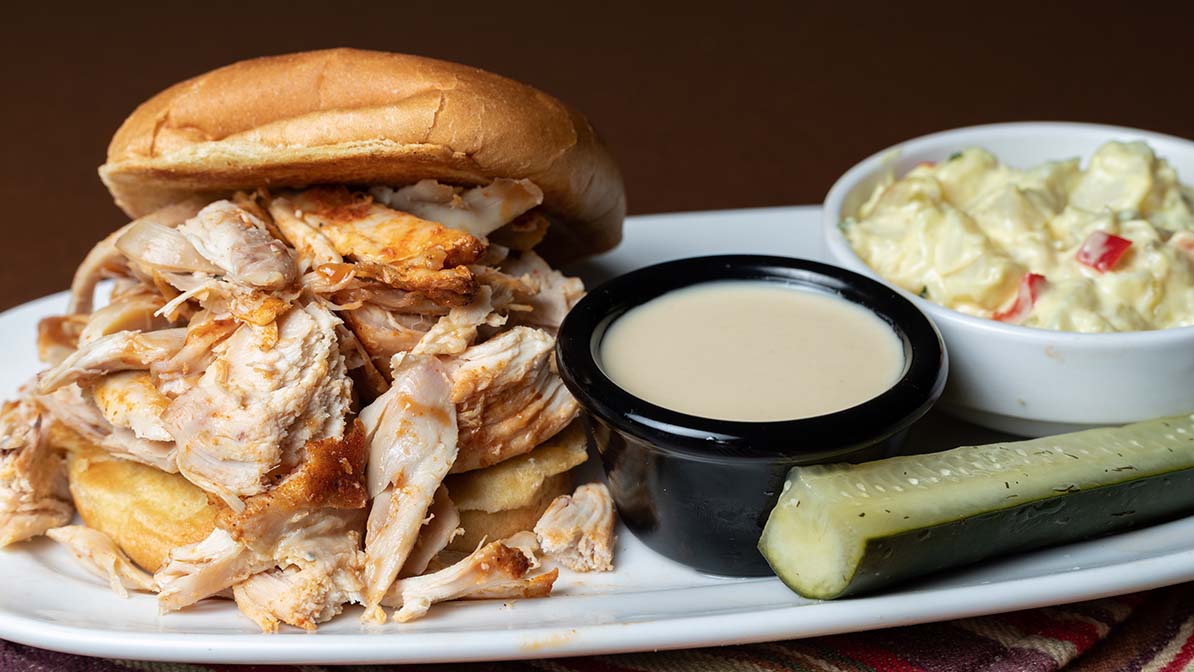 Hand Held Pulled Chicken Sandwich with potato salad and pickle